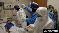 Nurses take a sample from Parham, a 7-year-old, to test for the coronavirus disease (COVID-19), at a hospital, in Tehran, Iran, July 8, 2020. (West Asia News Agency) 