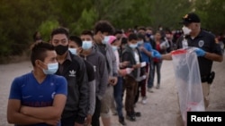 Unaccompanied minors from Central America line up to be transported by U.S. Customs officials, after crossing the Rio Grande into the United States from Mexico on rafts, in Penitas, Texas, March 26, 2021. 