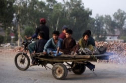 FILE - Boys from an Afghan refugee family ride on a motorcycle cart as they head to search for recyclables in a low-income neighborhood in Lahore, Pakistan, June 20, 2019.