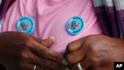 Yvette Demerit puts on a pin-back button in support of Amendment 4 at the Ben & Jerry's "Yes on 4" truck where people learned about Amendment 4 and eat free ice cream in Miami, Oct. 22, 2018.