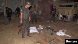 Security officials gather at the site of a suicide bomb blast in the outskirts of Dera Ismail Khan, Oct. 16, 2013. 