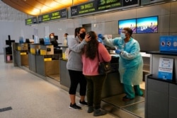 Licensed vocational nurse Caren Williams, left, collects a nasal swab sample from a traveler at a COVID-19 testing site at the Los Angeles International Airport in Los Angeles, Nov. 23, 2020.