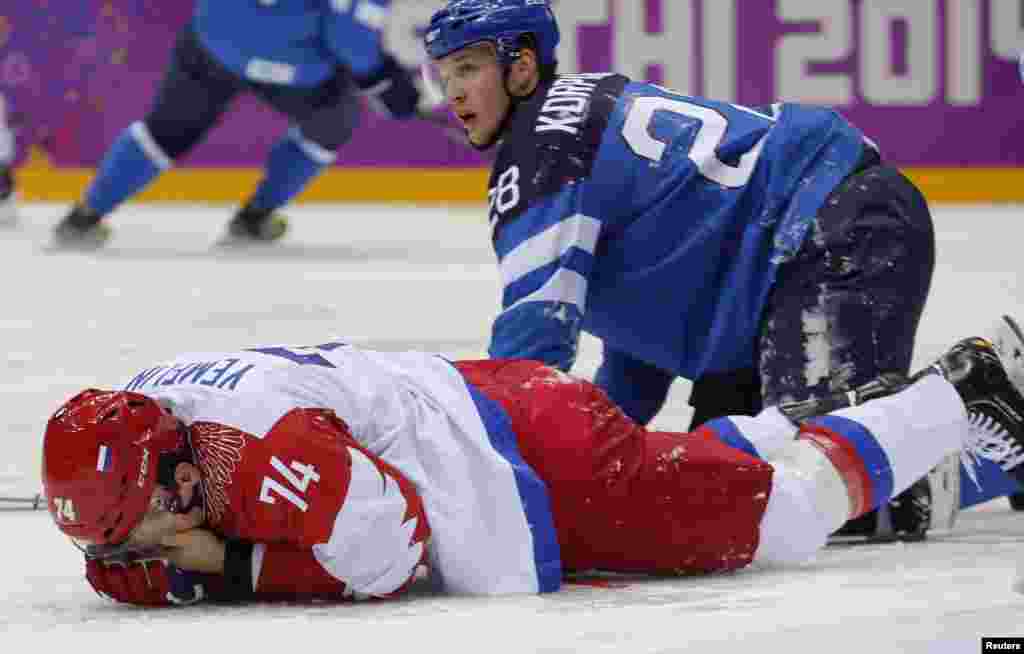 Russia's Alexei Yemelin holds his face after getting hit by Finland's Lauri Korpikoski (right) during the second period of the men's quarter-finals ice hockey game, Sochi, Feb. 19, 2014. 