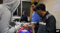 FILE - A paramedic treats an injured woman wounded by Israeli missile strikes at a hospital in Damascus, Syria, Nov. 20, 2019.