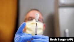 FILE - In this Jan. 12, 2021, file photo a pharmacist draws saline while preparing a dose of Pfizer's COVID-19 vaccine in Sacramento, Calif. (AP Photo/Noah Berger, Pool, File)