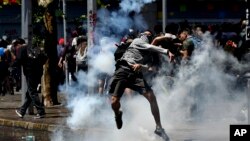 A protester returns a tear gas canister to police during clashes in Santiago, Chile, Oct. 21, 2019. 