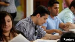 FILE - Ernesto Delgado, center, a Deferred Action for Childhood Arrivals (DACA) recipient, fills out his renewal application during the immigration ministry at Lincoln Methodist Church in Chicago, Sept. 10, 2017. 