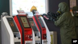 Petugas berseragam dari tim 'hazmat' atau bahan berbahaya memindai mesin-mesin di bandar udara internasional Kuala Lumpur (26/2). (AP/Daniel Chan)
