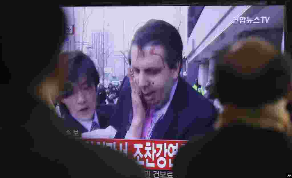 South Korean men watch a TV news program reporting that U.S. Ambassador to South Korea Mark Lippert was injured in a knife attack in Seoul, March 5, 2015.