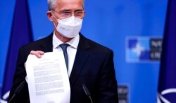 FILE - NATO Secretary-General Jens Stoltenberg holds up a ministerial statement on Afghanistan as he attends a media conference at NATO headquarters in Brussels, April 14, 2021.