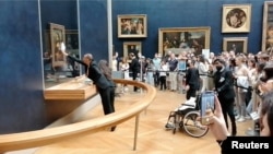 Museum staff clean the protective glass with da Vinci's Mona Lisa behind it, after a visitor smeared it with cream, in Paris