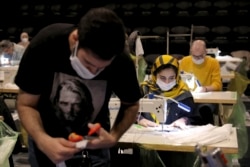 Volunteers wearing face masks to curb the spread of the new coronavirus sew masks for poor people at the Hafez theater hall in downtown Tehran, Iran, April 15, 2020.