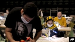 Volunteers wearing face masks to curb the spread of the new coronavirus, sew face masks for poor people, at the Hafez theatre hall in downtown Tehran, Iran, April 15, 2020.