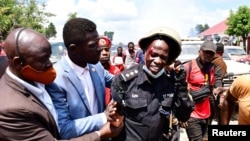 Ugandan pop star and presidential candidate Robert Kyagulanyi, also known as Bobi Wine, assists one of his bodyguards who was injured in clashes between Wine's supporters and security forces in Kayunga district near Kampala, Uganda, Dec. 1, 2020.