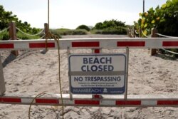 FILE - A sign is posted at a closed entrance to the beach during a spike in coronavirus cases, in the South Beach neighborhood of Miami Beach, Florida, July 3, 2020. Beaches will reopen Tuesday.