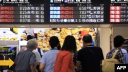 Passengers look at a noticeboard at Osaka station in Osaka, western Japan, as trains are delayed up to three hours due to rains from Typhoon Nangka, July 17, 2015.