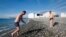 A man walks out of the sea after swimming during sunny spell at the Olympic Park in Sochi, Feb. 12, 2014.