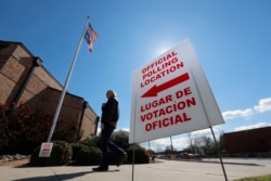 FILE - A sign points potential voters to an official polling location during early voting in Dallas, Feb. 26, 2020.