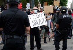 A participant in a protest over the death of George Floyd, a handcuffed black man in police custody in Minneapolis, squares off with Denver police officers, May 29, 2020, in Denver.