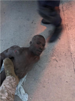 Alleged gang leader Arnel Joseph lies on the ground as police puts boot on his chest.