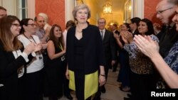 Staff members applaud as Britain's new Prime Minister Theresa May walks into 10 Downing Street after May met Queen Elizabeth in Buckingham Palace, in central London, Britain, July 13, 2016.