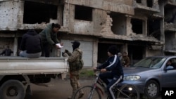 A member of the new armed forces, a former rebel who took part in the overthrow of Bashar Assad's government, checks the ID of a person at a checkpoint in the district of Khalidiya, Homs, Syria, Jan. 1, 2025.
