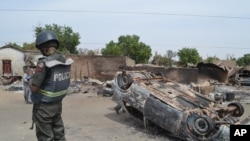 FILE - Nigerian policeman guards scene of attack by suspected Islamic extremists in Kawuri, Maiduguri, in January 2014.