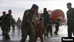 An Afghan National Army officer escorts a slightly injured boy from the site of a suicide attack on the outskirts of Mazar-e-Sharif, Afghanistan, Feb. 8, 2016.