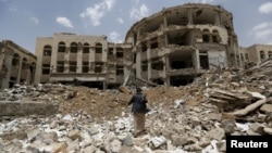 A Houthi militant walks in front of a government compound, destroyed by recent Saudi-led air strikes, in Yemen's northwestern city of Amran July 27, 2015.