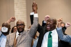 Philonise Floyd, brother of George Floyd, left, and attorney Ben Crump, right, raise their hands in triumph during a news conference after the murder conviction against former Minneapolis police officer Derek Chauvin, April 20, 2021.