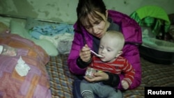 Ольга Шевченко та її 6-місячний син Євген у бомбосховищі на Харківщині. 12 жовтня 2022. REUTERS/Vyacheslav Madiyevskyy