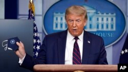 President Donald Trump holds a face mask as he speaks during a news conference at the White House, July 21, 2020.