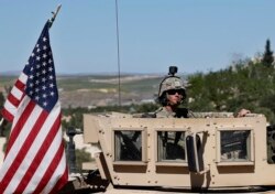 FILE - A U.S. soldier sits in an armored vehicle on a road leading to the tense front line with Turkish-backed fighters, in Manbij, north Syria, April 4, 2018.
