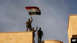 Iraq's elite counterterrorism force soldiers raise an Iraqi flag over the main church in Bartella, Iraq, Oct. 21, 2016.