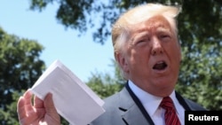 President Trump holds up what he described as a deal with Mexico on immigration and trade at the White House, June 11, 2019.