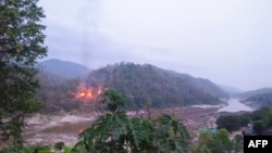 Kebakaran di pangkalan militer Myanmar, sepanjang tepi sungai Salween, terlihat dari kota Mae Sam Laep, provinsi Mae Hong Son Thailand, setelah pangkalan itu diserang oleh Persatuan Nasional Karen (KNU) . (KAWTHOOLEI TODAY / AFP)
