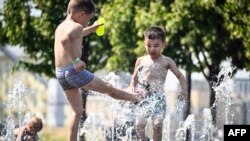 Children play in a fountain during a midday heat in central Moscow on July 3, 2024.