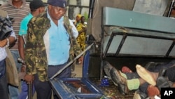 An armed police officer stands guard over the bodies of six attackers who were killed as they tried to gain entry into a military barracks on the coast, in Mombasa, Kenya, Nov. 2, 2014.