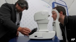 Jorge Cuadros, left, gives a demonstration of a robotic retinal camera to a reporter at the Google I/O conference in Mountain View, California, May 8, 2018.