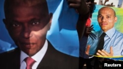 FILE - Supporters of main opposition Senegalese Democratic Party hold posters of former Senegalese president Abdulaye Wade (L) and his son Karim (R) during a protest in Dakar April 23, 2013.