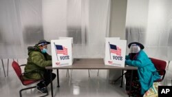 Two voters fill out ballots during early voting at the Cuyahoga County Board of Elections, Oct. 6, 2020, in Cleveland.