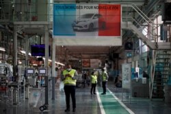 FILE - Workers, wearing face masks, are seen near the assembly line of Renault ZOE cars, as the French carmaker ramps up production with new security and health measures, in Flins, France, May 6, 2020.