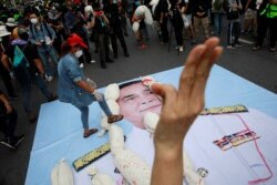 A protester places mock body bags representing COVID-19 victims on a picture of Thai Prime Minister Prayut Chan-O-Cha during an anti-government protest in Bangkok, Thailand, July 18, 2021.
