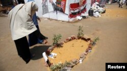 Members of the Muslim Brotherhood and supporters of ousted Egyptian President Mohamed Morsi walk near the mock grave of a protester who was killed yesterday during clashes around Cairo University and Nahdet Misr Square in Giza, Cairo, Egypt, July 23, 2013.