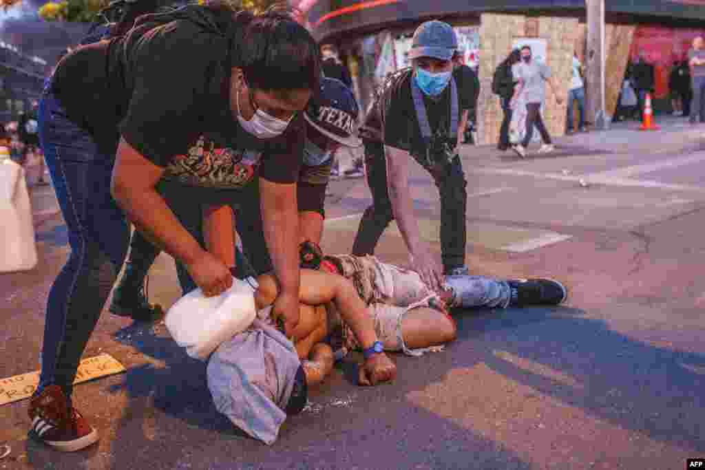 People pour milk onto the face of an injured man during a protest outside the Third Police Precinct on May 28, 2020 in Minneapolis, Minnesota, over the death of George Floyd, an unarmed black man, died after a police officer kneeled on his neck for…