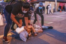 People pour milk onto the face of an injured man to wash pepper spray out of his eyes during a protest outside the Third Police Precinct on May 28, 2020 in Minneapolis, Minn.