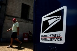 FILE - A man walks by a United States Postal Service mailbox in downtown Washington, August 19, 2020.