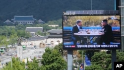 FILE - A TV screen shows a photo of South Korean President Moon Jae-in and North Korean leader Kim Jong Un, right, to promote the Seoul Defense Dialogue in Seoul, South Korea, Sept. 5, 2018. The sign reads: "Peace on the Korean Peninsula."