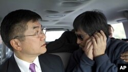 In this photo released by the US Embassy Beijing Press Office, blind lawyer Chen Guangcheng makes a phone call as he is accompanied by U.S. Ambassador Gary Locke on the way to a hospital in Beijing, May 2, 2012.