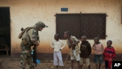 A French soldier talks to curious children as he mans a roadblock in the Miskine neighborhood of Bangui, Central African Republic, Jan. 6, 2014. 